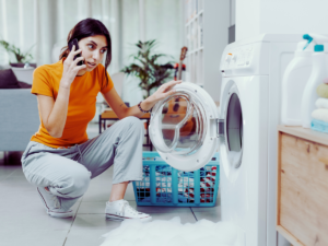 woman calling plumbing after washing machine flood caused by caused laundry drain clog